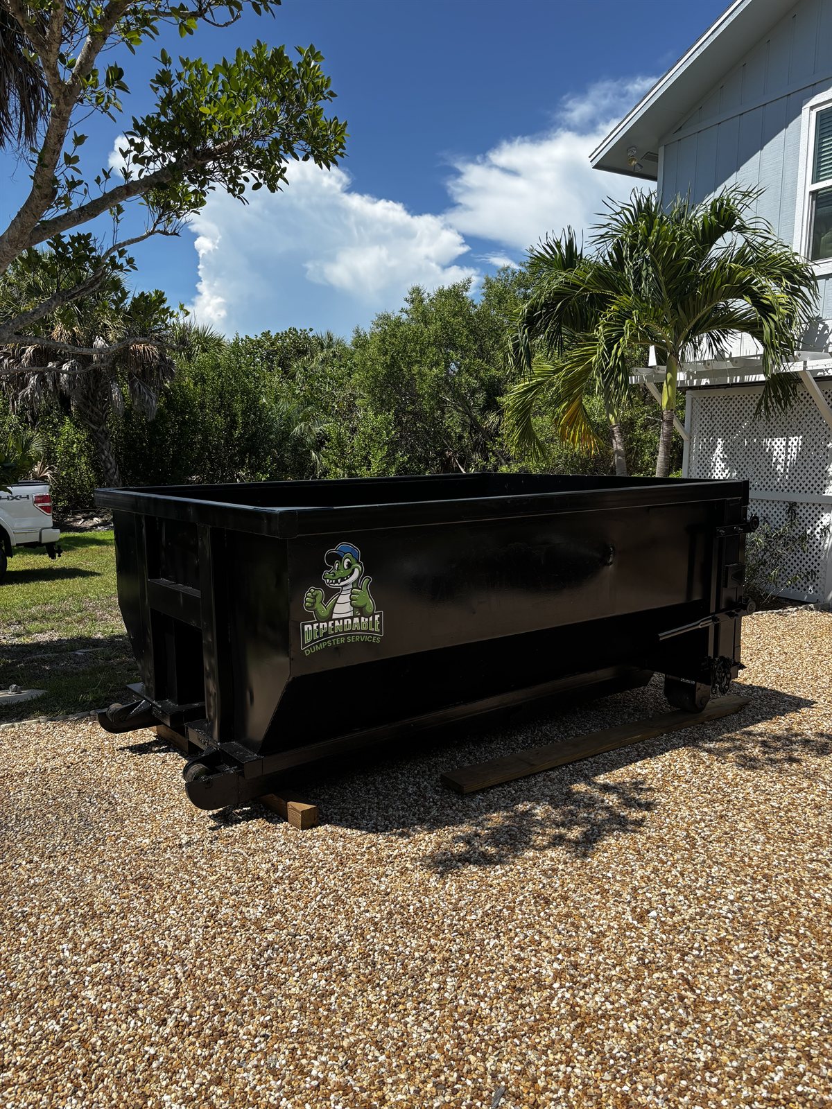 Dependable Dumpster Services 10-yard roll-off dumpster on a shell driveway beside a Southwest Florida home
